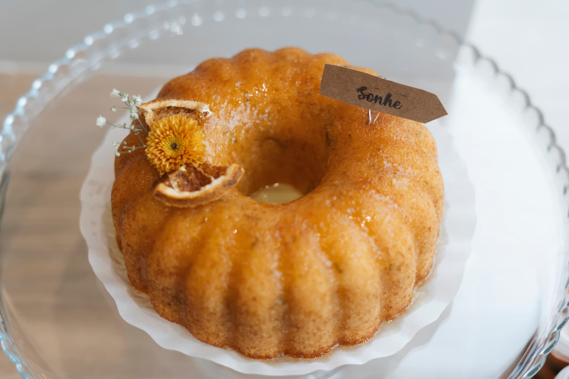Bolo de laranja com calda brilhante e plaquinha escrita Sonhe